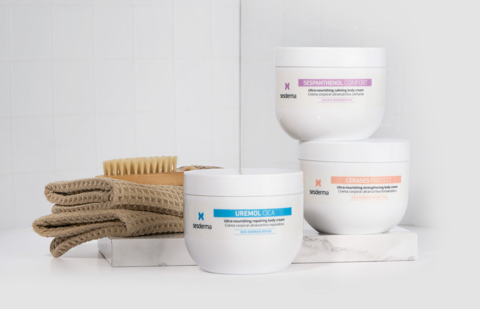 Imagen de tres cremas corporales apoyadas en soporte de marmol