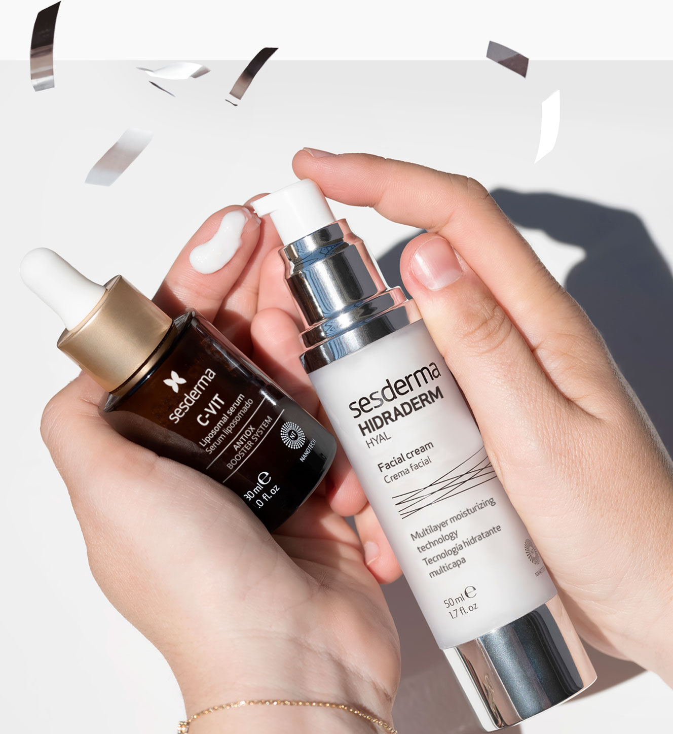 Imagen manos sosteniendo dos productos Sesderma y confeti alrededor